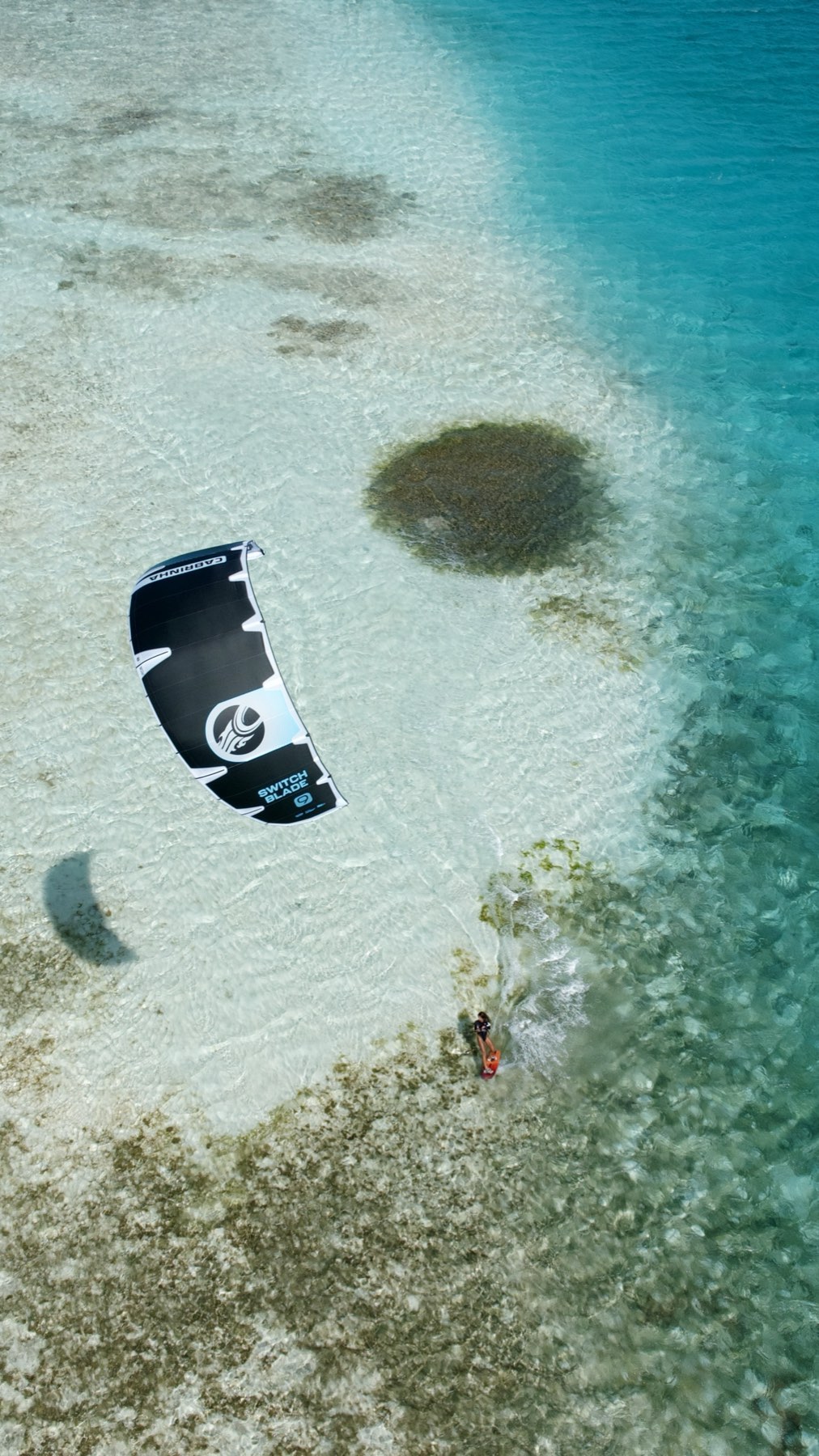 Manu La Porta velejando de kitesurf sobre água cristalina, vista aérea